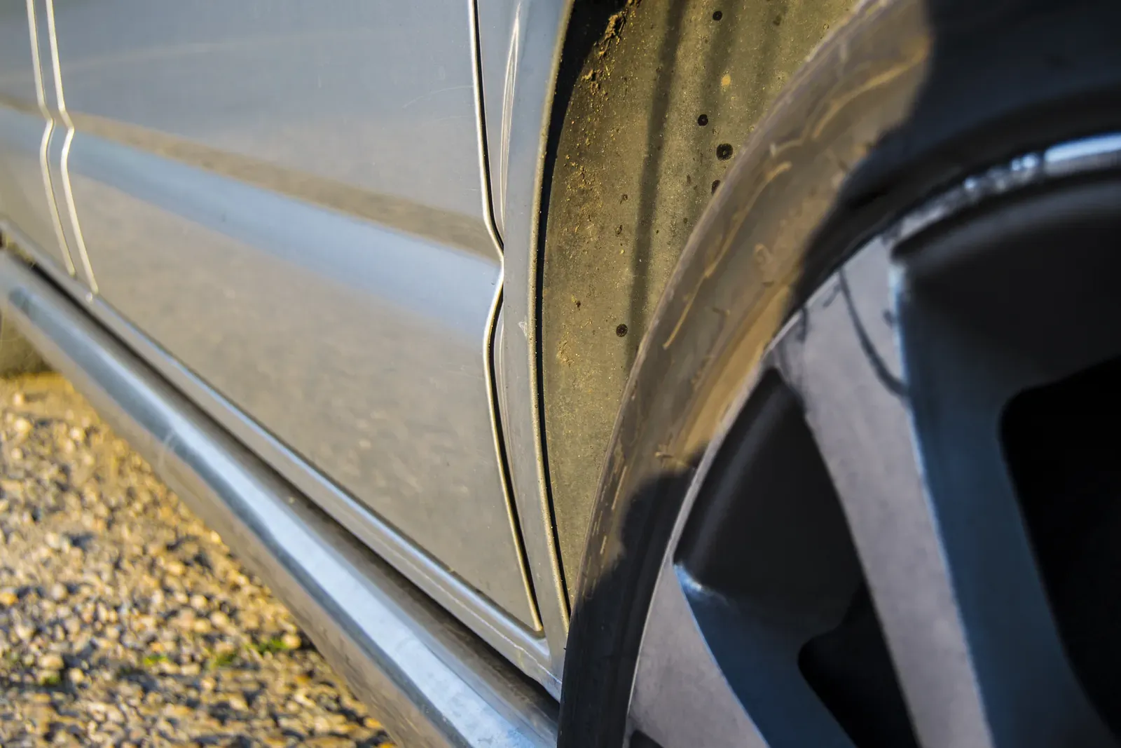 Close-up of an alloy wheel and dirt-streaked arch on a silver car's lower panel