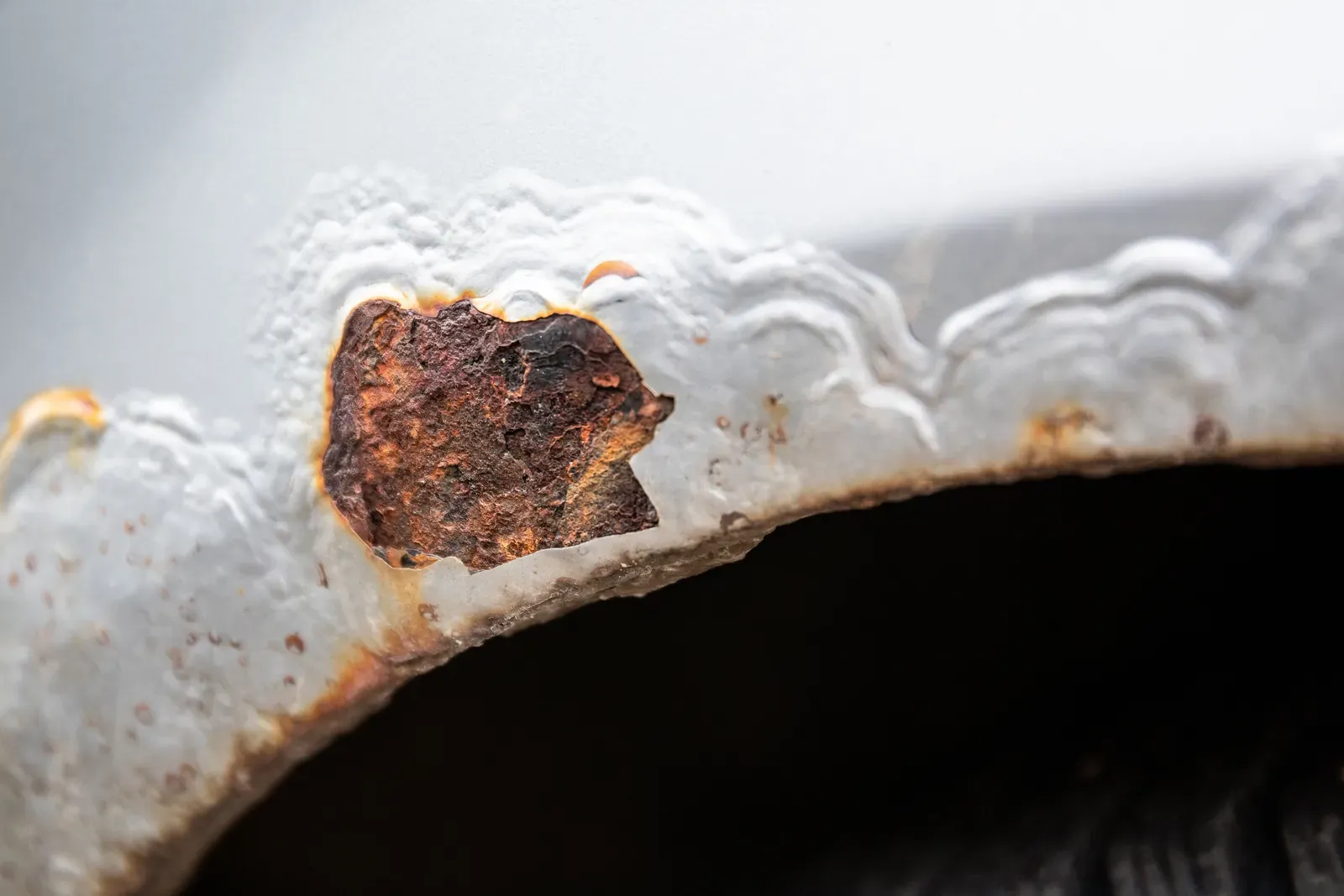 Bubbling paint and a large rust hole breaking through a wheel arch edge