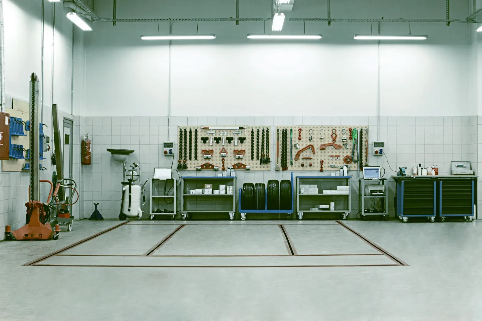 A tidy workshop wall with pegboards of tools, carts and stacked tires