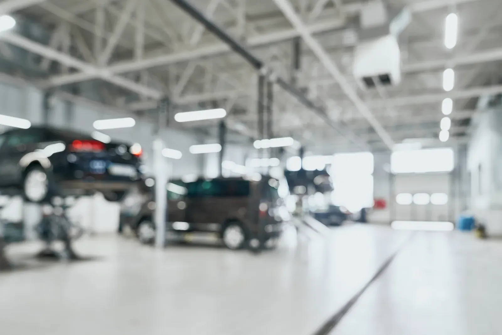 A softly blurred service centre with vehicles raised on lifts
