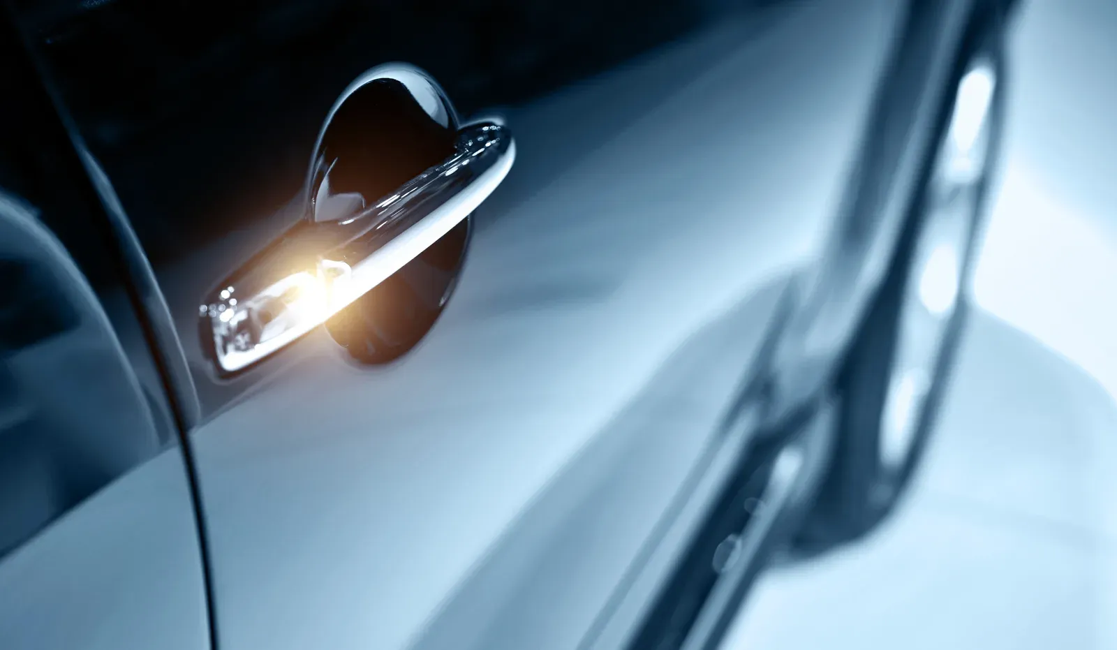Blue-toned close-up of a chrome door handle on a glossy panel